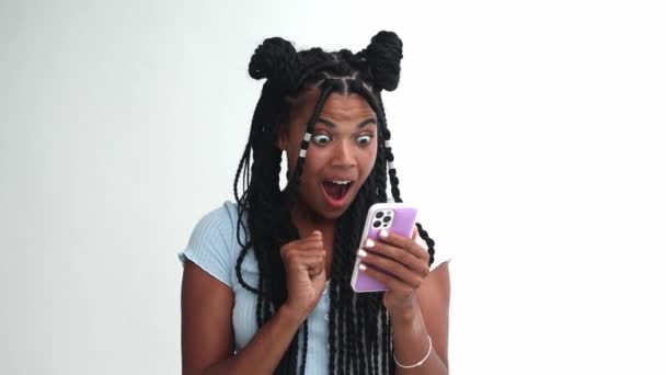 Délicieuse étonnante femme multiethnique se réjouit, exprimant surprise tout en obtenant de bonnes nouvelles sur son smartphone - Séquence, vidéo