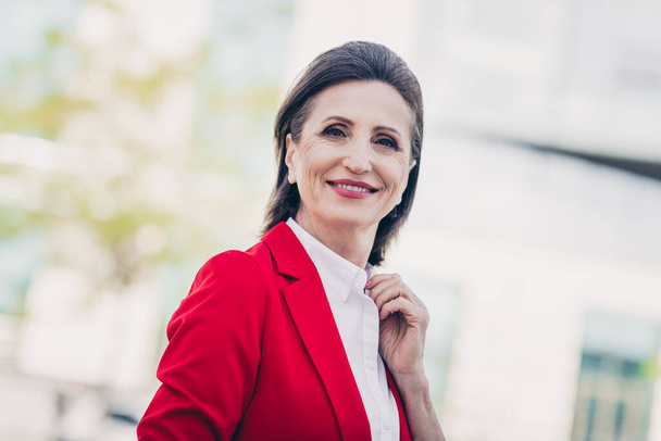 Photo of charming sweet mature lady leader wear red jacket walking smiling outside city business complex. - Zdjęcie, obraz