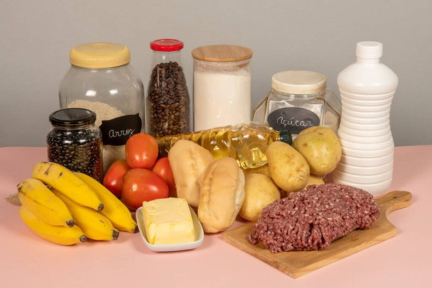 Brazilian basic food basket completed composed of 13 products: meat, milk, rice, beans, bread, flour, potato, tomato, bread, coffee, banana, sugar, oil and butter - Photo, Image