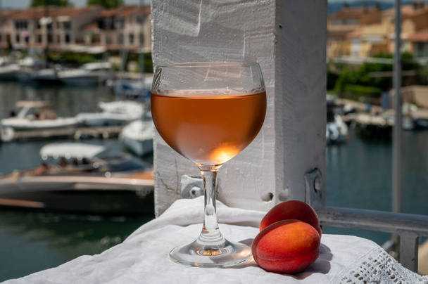 Trinken von kaltem Rosenwein aus der Provence mit roten Aprikosen und Blick auf den Yachthafen von Port Grimaud, Sommerurlaub an der französischen Riviera, Frankreich - Foto, Bild
