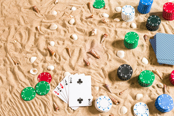 Apuestas en concepto de vacaciones - arena blanca con conchas marinas, fichas de póquer de colores y cartas. Vista superior. Copiar espacio. Verano
 - Foto, imagen