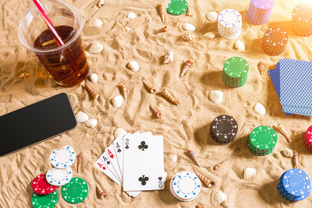 Gambling on vacation concept - white sand with seashells , colored poker chips and cards. Top view. Copy space. Summer. Sun flare - Photo, Image