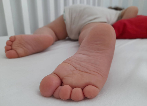 Jalka vauva hänen pinnasänky kun hän nukkuu - Valokuva, kuva