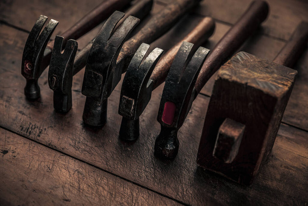 collection of carpentry hammers on top of old vintage workbench for manual work  - 写真・画像