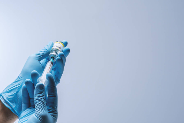 Manos en guantes de látex azul con vacuna del vial de vidrio. Salud y concepto médico. - Foto, imagen