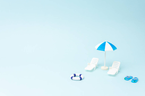 Creative background with sunbeds and sun umbrella on pastel blue background. Summer holiday concept. - Фото, зображення