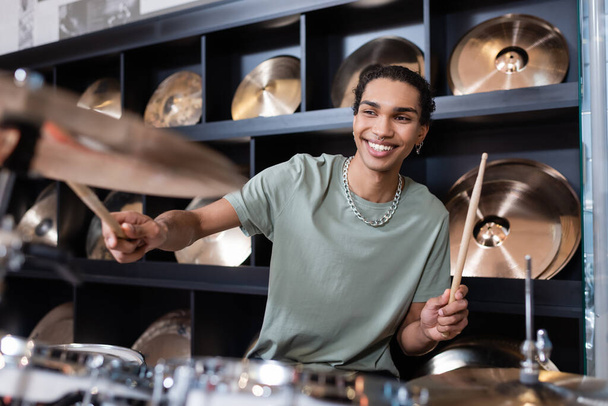 Young african american customer performing drums in music store  - 写真・画像