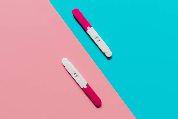positive and negative pregnancy tests on blue and pink backgrounds - 写真・画像