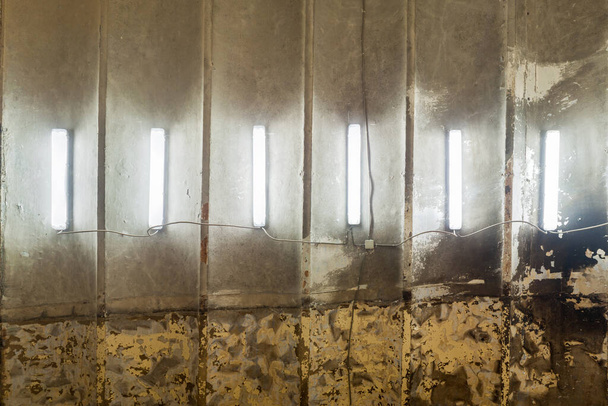 row of CFL fluorescent lamps on burned ceiling of abandoned building, flat full-frame background and texture - Fotó, kép