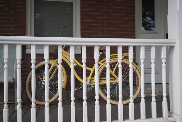 The yellow vintage bicycle is behind the pillars on the porch. - Foto, imagen