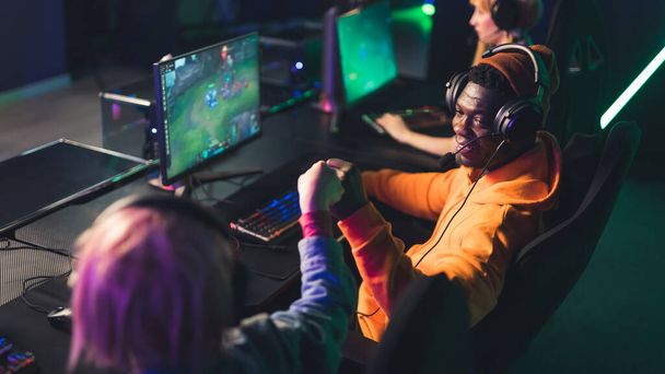 African american bearded casually dressed man wearing headset playing a popular online team game, doing a fist bump with another player. High quality photo - Photo, Image
