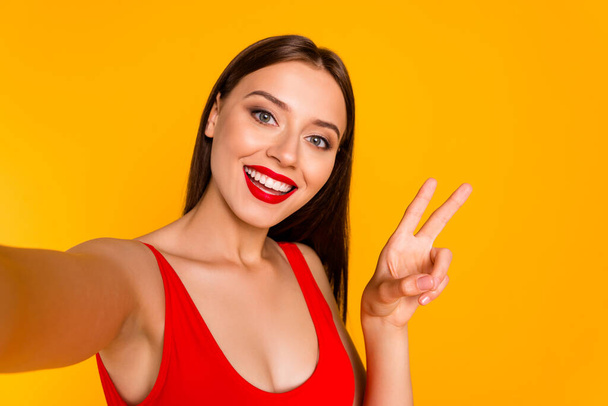 Photo of cool pretty lady dressed bodysuit recording self video showing v-sign isolated yellow color background. - Fotografie, Obrázek