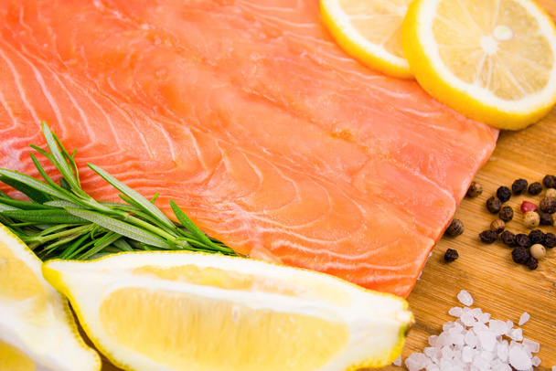 Salmon fillet with lemon and rosemary on a wooden board. Red fish with spices. - Photo, Image