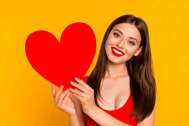 Photo of sweet adorable lady dressed bodysuit holding big red heart smiling isolated yellow color background. - Zdjęcie, obraz