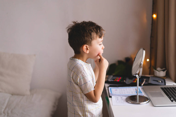Speech therapy concept. Cute little boy pronouncing sound O looking at mirror doing an online Speech therapy lesson through a laptop - Photo, Image