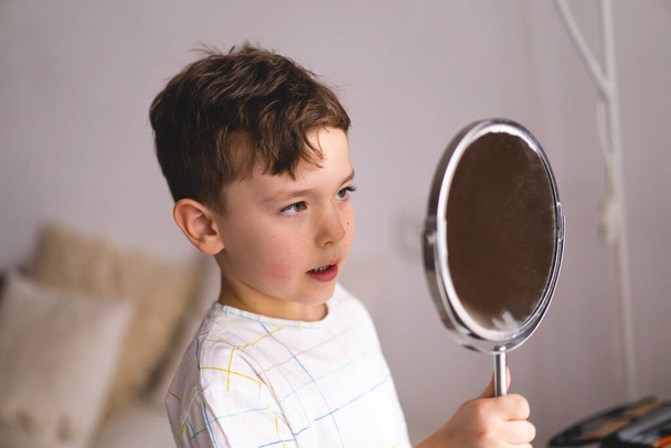 Концепция логопедии. Симпатичный маленький мальчик произносит звук О, глядя на зеркало делает онлайн урок логопедии через ноутбук - Фото, изображение