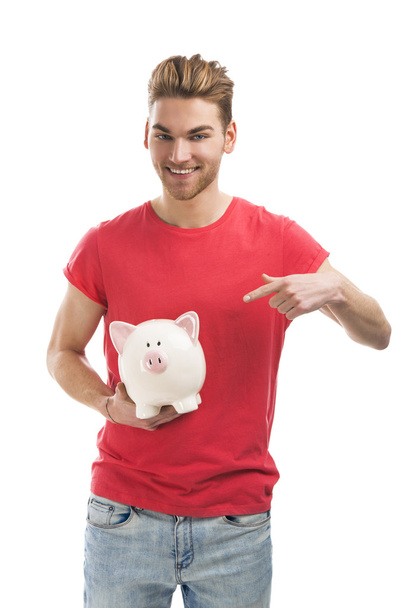 Handsome young man holding a piggy bank - Zdjęcie, obraz