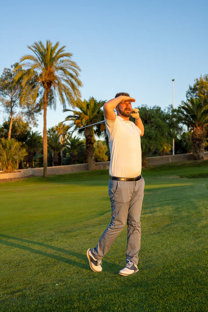 Guter Schlag, Golfer schwingt seinen Chauffeur und schaut weg, während er auf dem Golfplatz steht, Golfprofi sucht Flugbahn des Balls. - Foto, Bild
