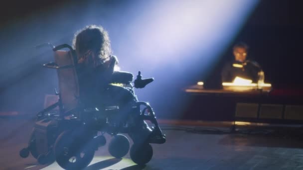 Eine Frau mit spinaler Muskelatrophie beim Vorsprechen auf einer von einem Scheinwerfer beleuchteten Theaterbühne mit einem Regisseur der Aufführung - Filmmaterial, Video