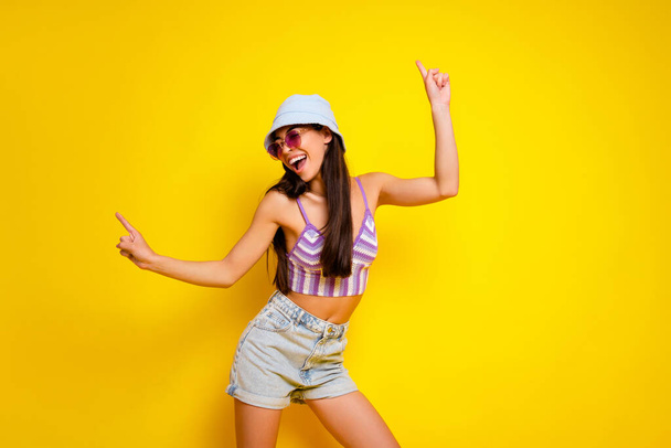 Photo of pretty shiny girl dressed swimsuit bra cap pointing empty space dancing isolated yellow color background. - 写真・画像