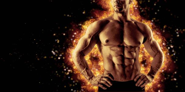 Brutal strong athletic Bodybuilder posing. Fire and spark explosion in the background. Bodybuilding and healty life concept. - Fotoğraf, Görsel