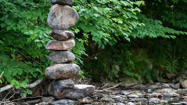 Грубый камень Кэрнс гордо стоит в мелководье ручья - Фото, изображение