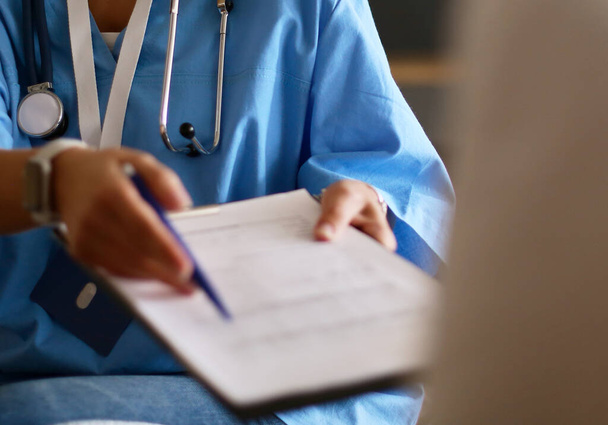 Female doctor hand hold silver pen filling patient history list at clipboard pad - Φωτογραφία, εικόνα