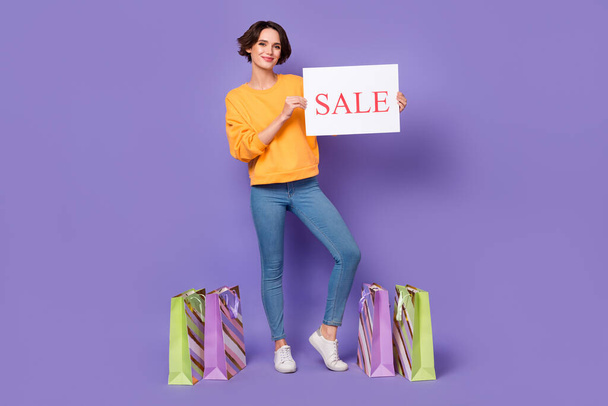 Full length body size view of attractive cheerful girl holding sale board presents gifts isolated over violet lilac color background. - Fotografie, Obrázek