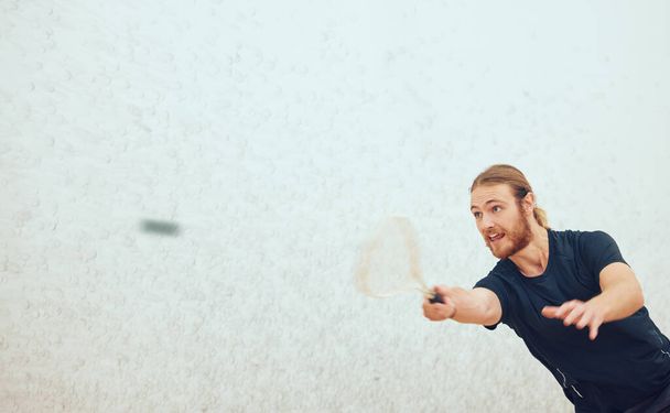 Sportowy młody squash gracz uderzając piłkę podczas gry na boisku z copyspace. Aktywny, biały mężczyzna trenujący i uprawiający sport w samym centrum sportowym. Zdrowe serce i rozmycie ruchu - Zdjęcie, obraz