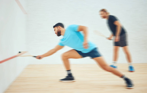 Two athletic squash players playing match during competitive court game. Fit active mixed race and caucasian athlete competing during training challenge in sports centre. Full length with motion blur. - Photo, Image