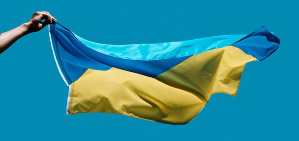 Nahaufnahme eines Mannes, der die ukrainische Flagge am Himmel hisst, in einem Panoramaformat, das als Web-Banner oder Header verwendet werden kann - Foto, Bild