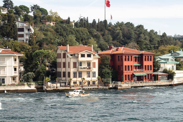 View of a small fishing boat on Bosphorus and historical and traditional mansions in Kandilli area of Asian side of Istanbul. It is a sunny summer day. Beautiful scene. - Zdjęcie, obraz