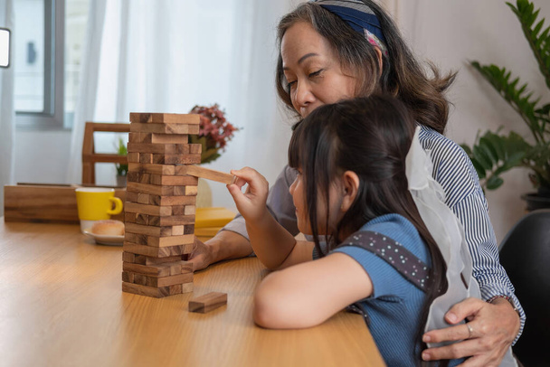 Grandmother and granddaughter play games. Blockwood Puzzle To develop skills for granddaughter and as a holiday activity - Foto, afbeelding