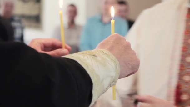 Man holds two candles in a temple in a traditional Ukrainian dress at christening. Hands close up - Footage, Video