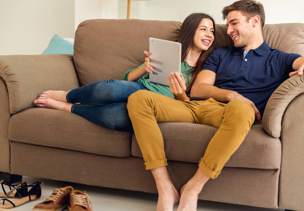 Young couple sitting on the sofa and watching something on a tablet - Foto, immagini