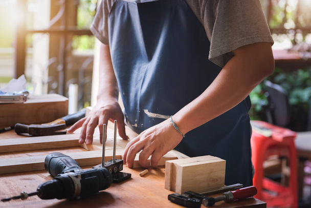 Unternehmer Woodwork misst die Bretter, um die Teile zu montieren und einen Holztisch für den Kunden zu bauen. - Foto, Bild