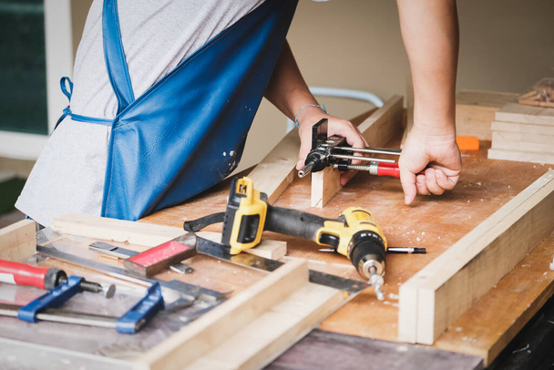 Woodworking operators are using woodworking tools to prepare a drill, drill holes in wood to assemble and build a wooden table for their customers. - Foto, Imagen
