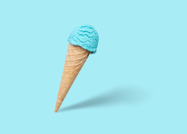 Blue ice cream scoop in cone, bright blue background - Foto, imagen