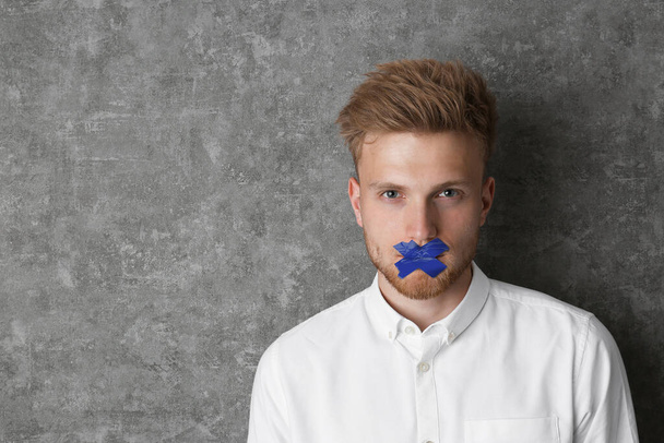 Man with taped mouth on grey background, space for text. Speech censorship - Fotografie, Obrázek