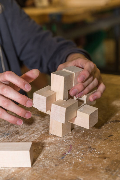 Человек строит тренировки памяти и головоломки Дьявольский узел - деревянный узел - Фото, изображение