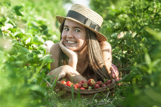 girl in strawberry field with basket of fresh picked berries - Fotoğraf, Görsel