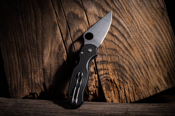Folding pocket knife with carrying clip. Knife on a wood background. Brown background. - Fotoğraf, Görsel