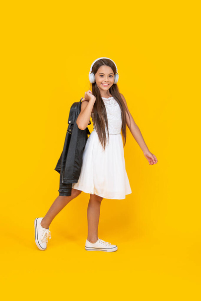 happy teen child listen music in headphones on yellow background. - Foto, afbeelding