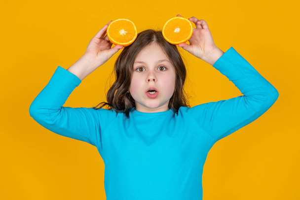 shocked teen girl hold orange fruit on yellow background. - Фото, зображення