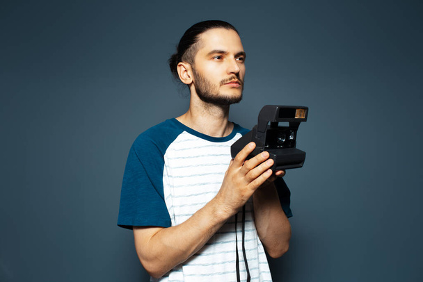Studio portrait of young man photographer making photo with polaroid camera. - Zdjęcie, obraz
