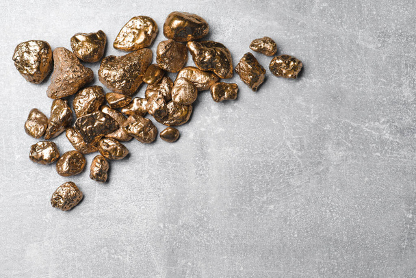 Pile of gold nuggets on light grey table, flat lay. Space for text - 写真・画像