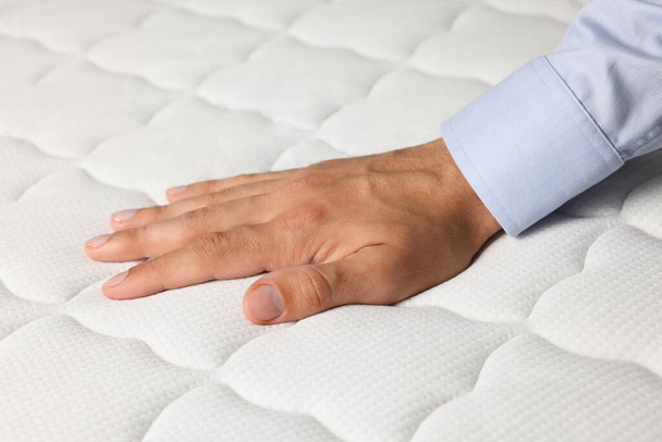Man touching soft white mattress, closeup view - Valokuva, kuva