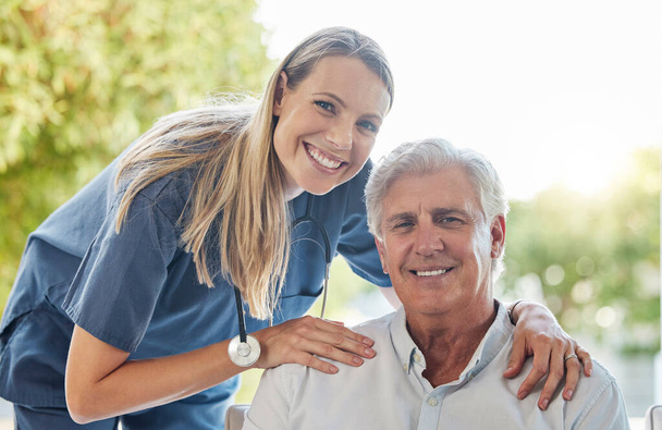 Szczęśliwy uśmiechnięty mężczyzna i kobieta pokazujący więź między pacjentem a lekarzem podczas badania kontrolnego w domu. Lekarz wykazujący wsparcie dla jej pacjenta podczas rekonwalescencji. - Zdjęcie, obraz