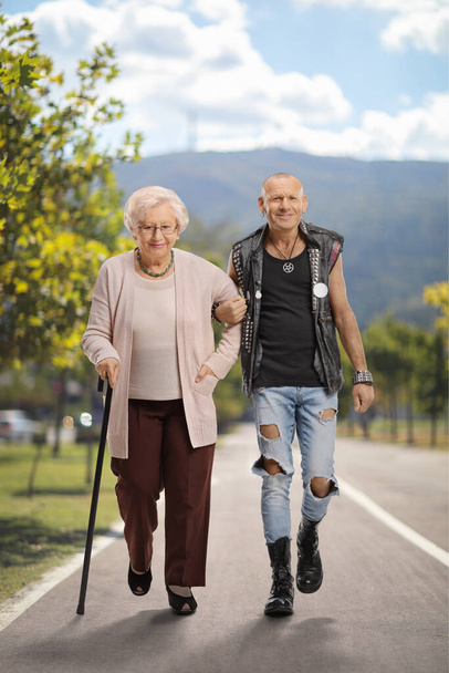 Man helping a senior woman with a walking cane on a pedestrian path - Foto, afbeelding
