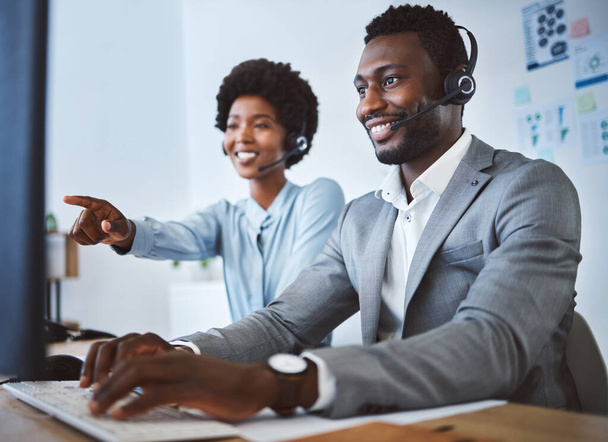 Szczęśliwy afrykański amerykański agent telemarketingu męskiego call center omawia plany z kolegą pracując razem nad komputerem w biurze. Rozwiązanie do rozwiązywania problemów przez dwóch konsultantów dla klienta - Zdjęcie, obraz